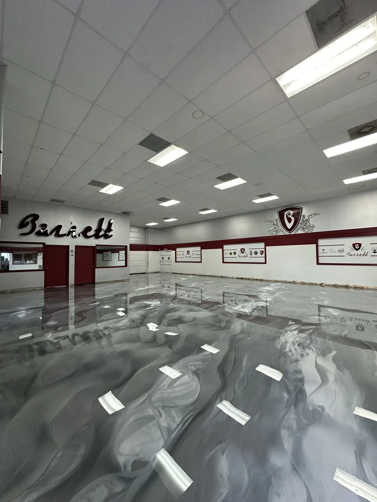 Gray metallic epoxy showroom floor at Barrett Auto Gallery with luxury cars, view 2