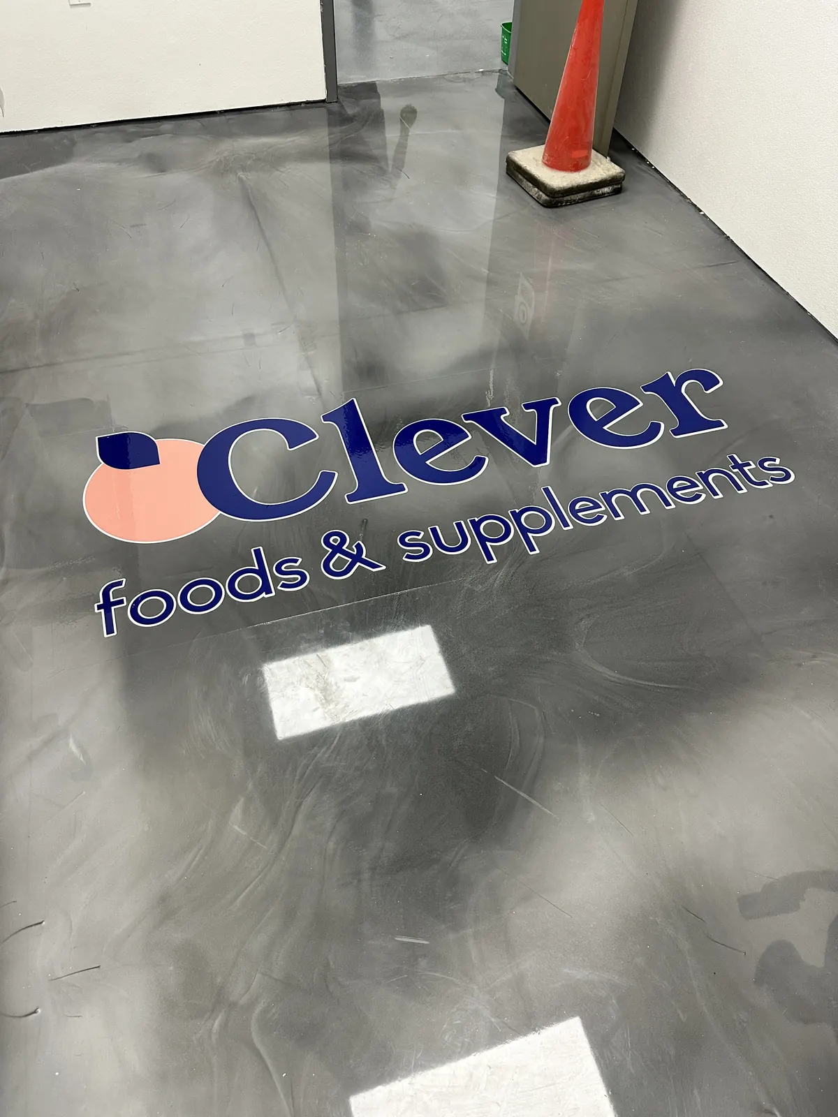 Gray metallic epoxy floor with the Clever Foods logo