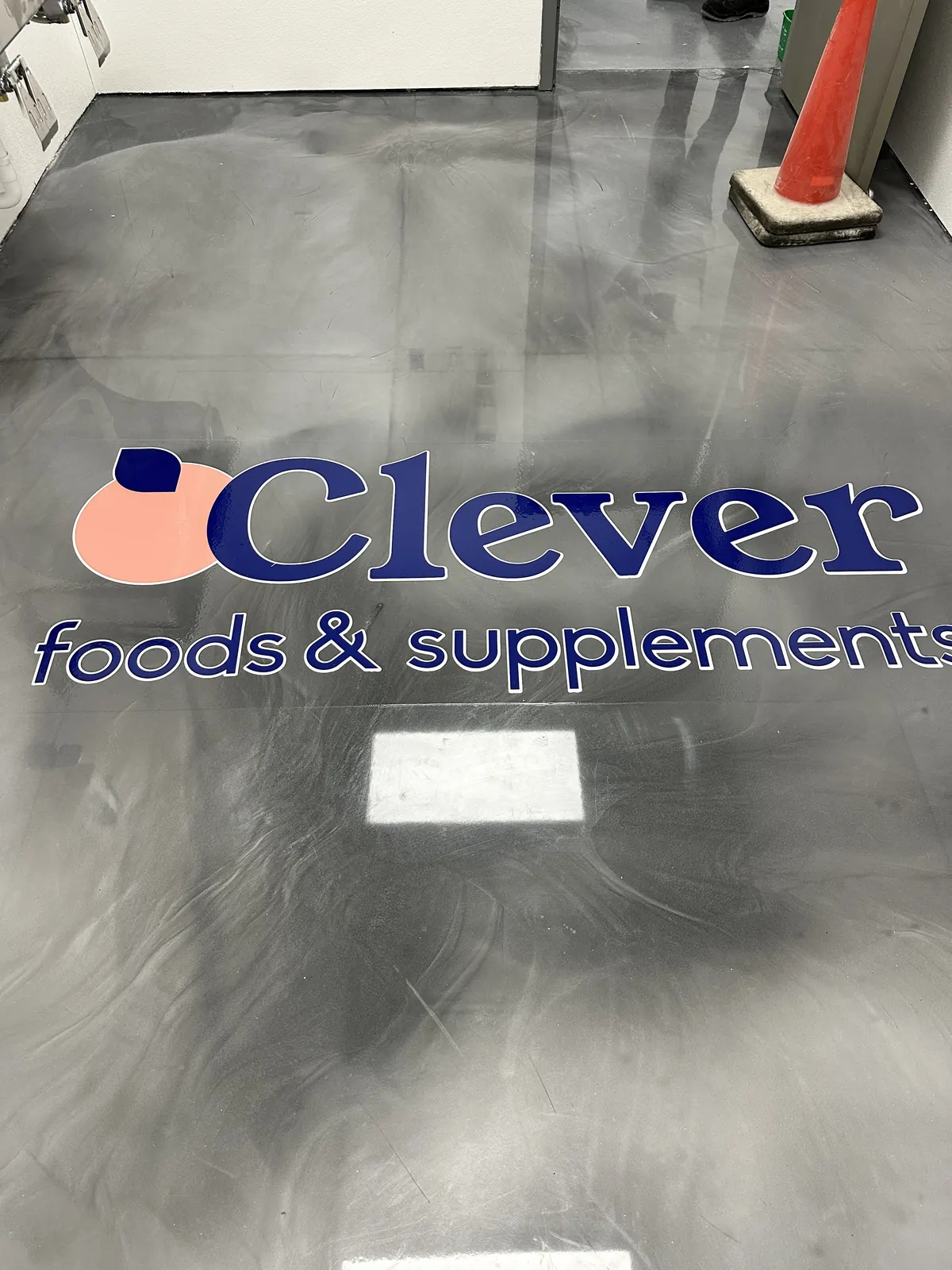 Gray metallic epoxy floor with the Clever Foods logo, view 2