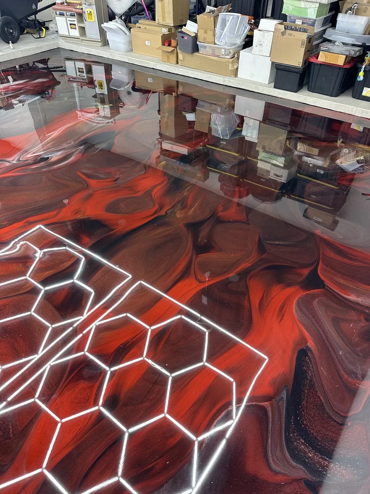 Red metallic epoxy floor under hexagon lights in a detailing studio, view 2