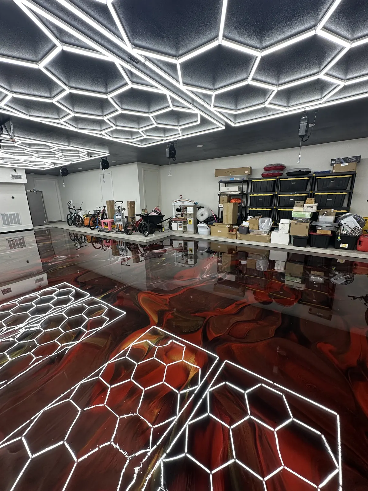 Red metallic epoxy floor under hexagon lights in a detailing studio, view 4