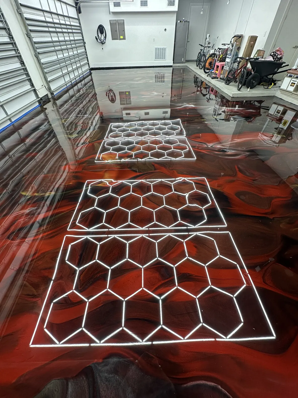 Red metallic epoxy floor under hexagon lights in a detailing studio, view 5